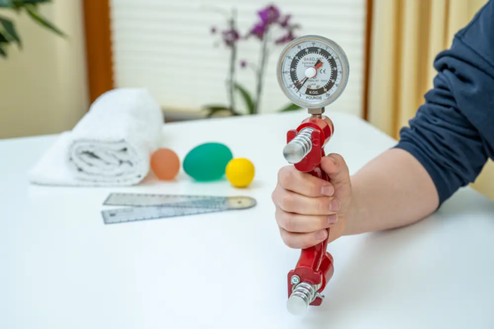 Eine Hand hält ein Fingerkraft-Messgerät